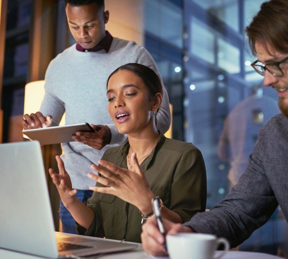 A diverse team collaborates in a modern office at night