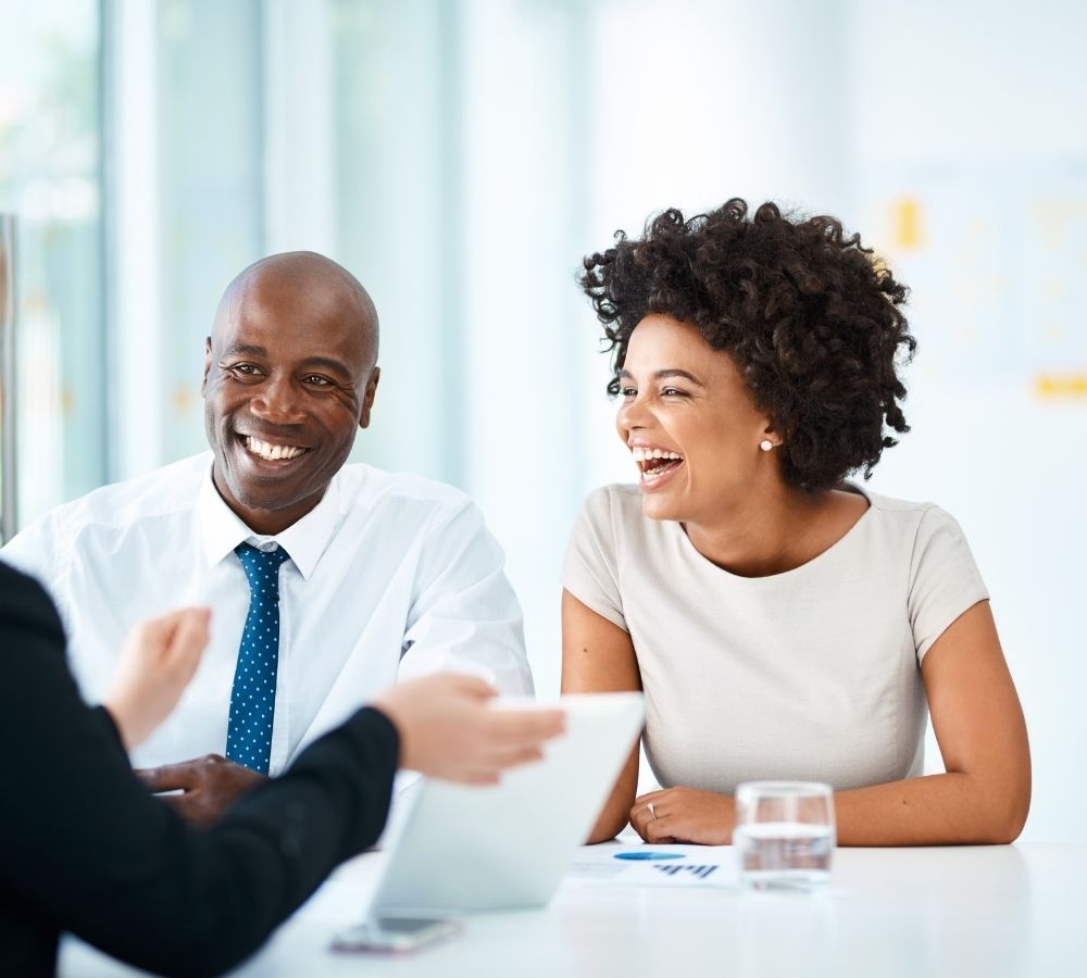 A man and a woman smiling and laughing in an office meeting