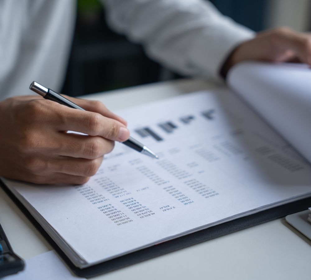 A person in a white shirt reviews financial documents with tables