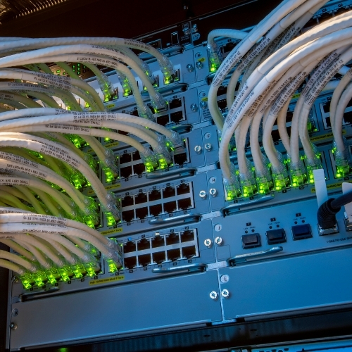 Rows of network switches with illuminated green lights and connected Ethernet cables create a complex (2)